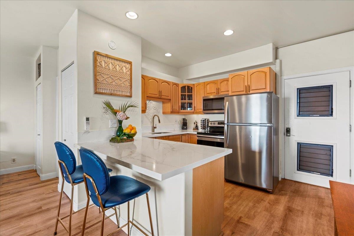 4435 Lower Honoapiilani Road, Unit 103 Lahaina, HI 96761 - Photo 28 of 34 a kitchen with stainless steel appliances granite countertop a refrigerator a stove a sink a dining table and chairs