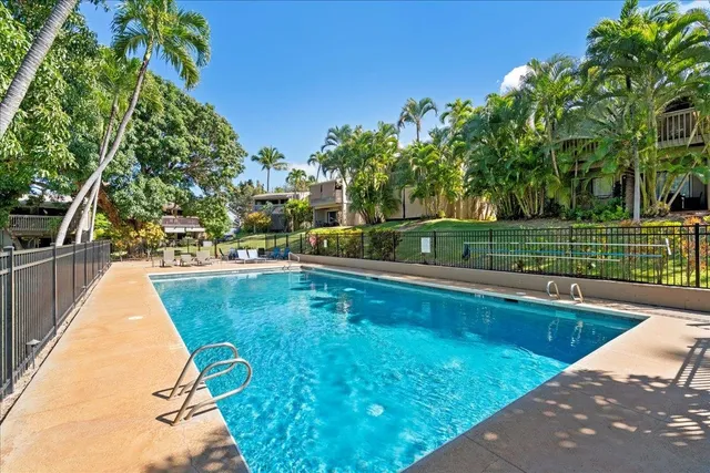 a view of a swimming pool with a lounge chair and trees in the background