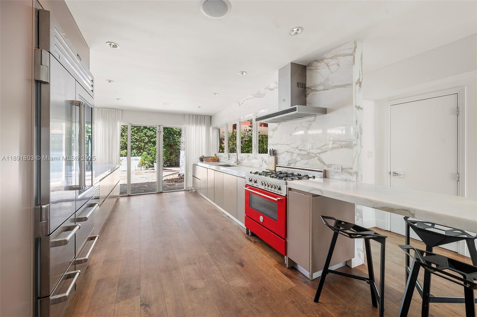2701 North Bay Road Miami Beach, FL 33140 - Photo 16 of 38 a large kitchen with stainless steel appliances a stove a sink dishwasher and a refrigerator with wooden floor
