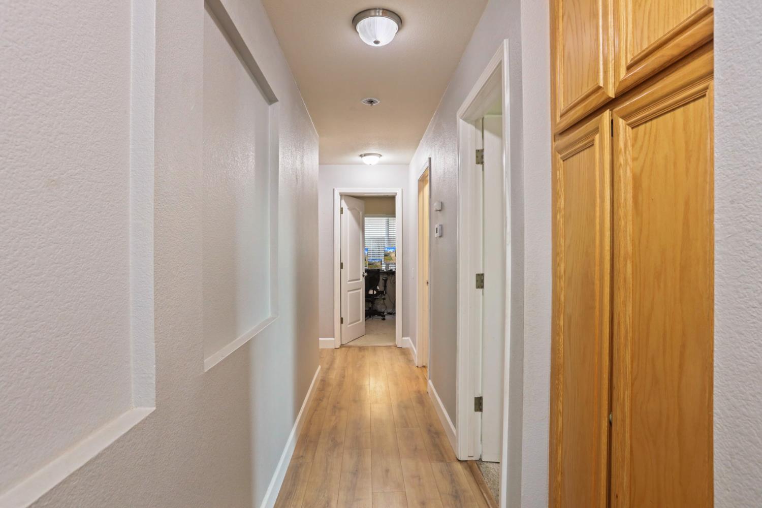 277 Fragrance Street Manteca, CA 95337 - Photo 14 of 27 a view of a hallway with wooden floor and a bathroom