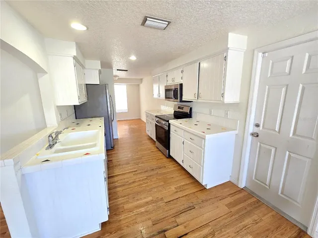 a large white kitchen with a stove a sink dishwasher and a refrigerator