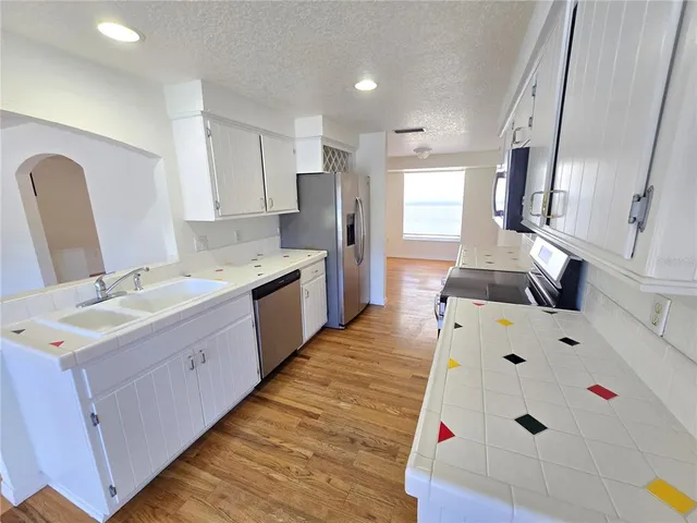 a large kitchen with a sink dishwasher stove and refrigerator with wooden floor