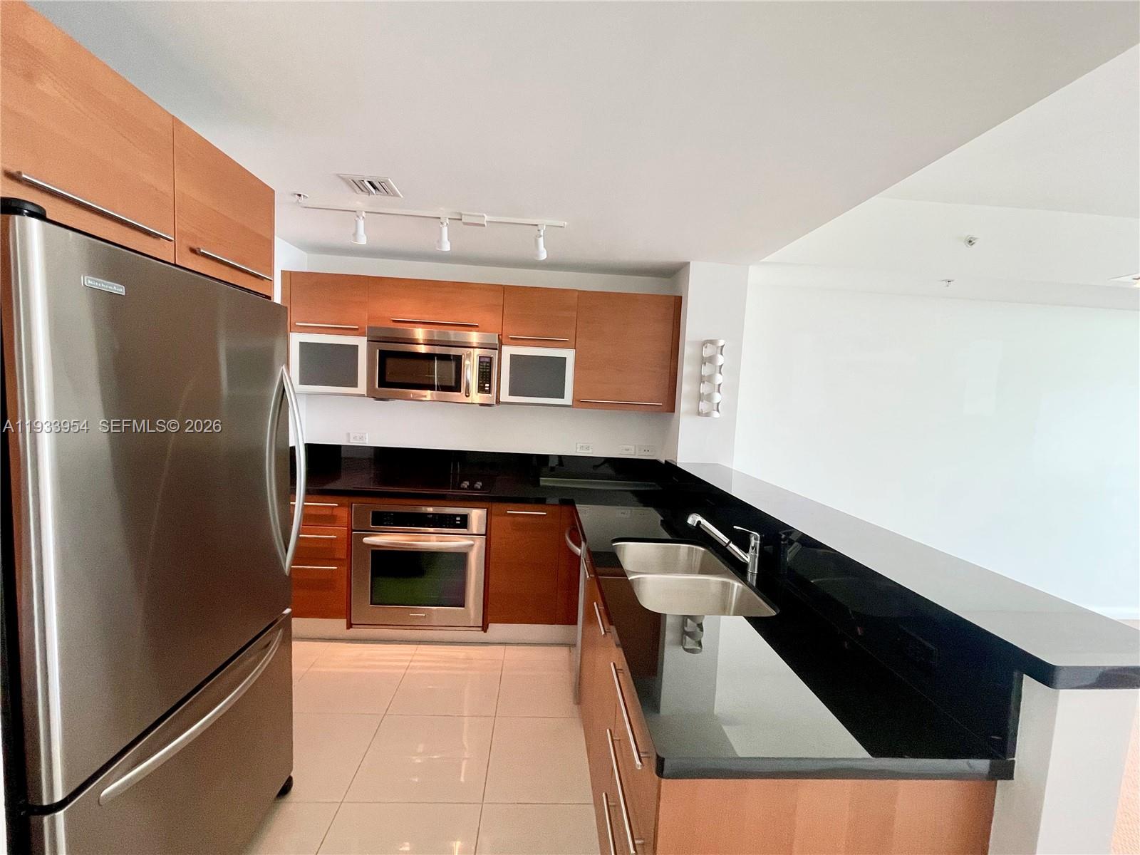 253 Northeast 2nd Street, Unit 2409 Miami, FL 33132 - Photo 11 of 61 a kitchen with stainless steel appliances granite countertop a refrigerator and a stove