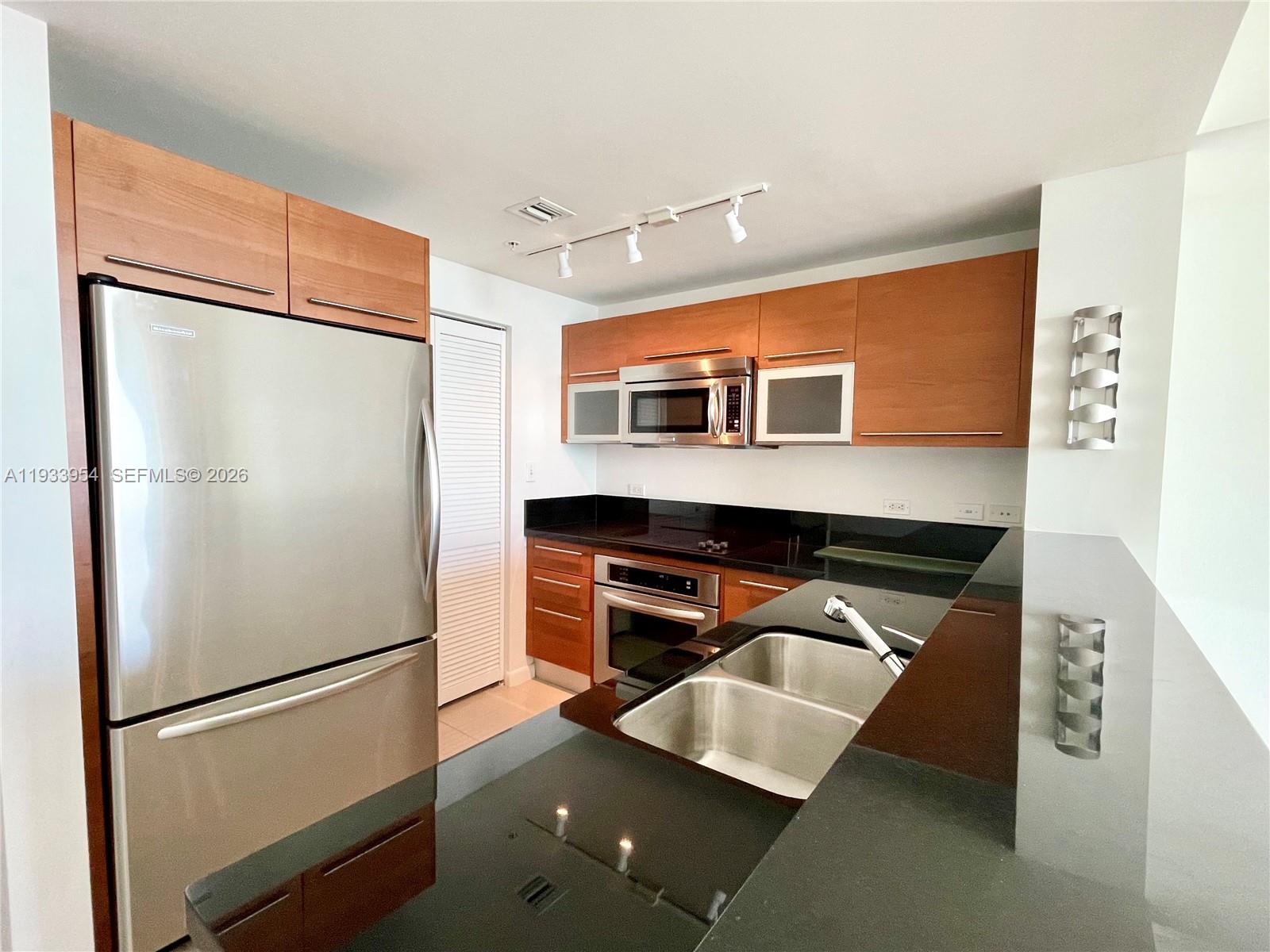 253 Northeast 2nd Street, Unit 2409 Miami, FL 33132 - Photo 12 of 61 a kitchen with stainless steel appliances granite countertop a refrigerator a stove and a sink with wooden floor