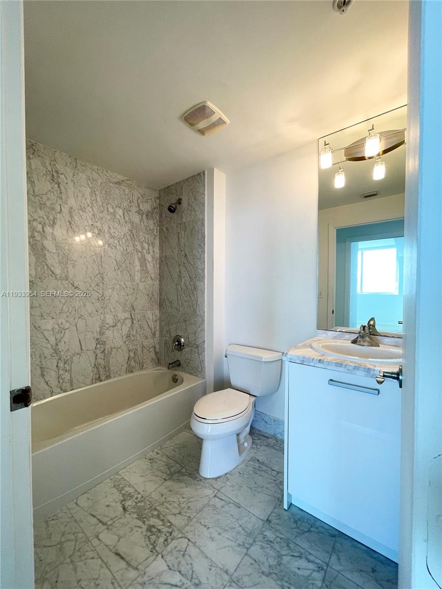 253 Northeast 2nd Street, Unit 2409 Miami, FL 33132 - Photo 32 of 61 a bathroom with a granite countertop sink a toilet a mirror and bathtub