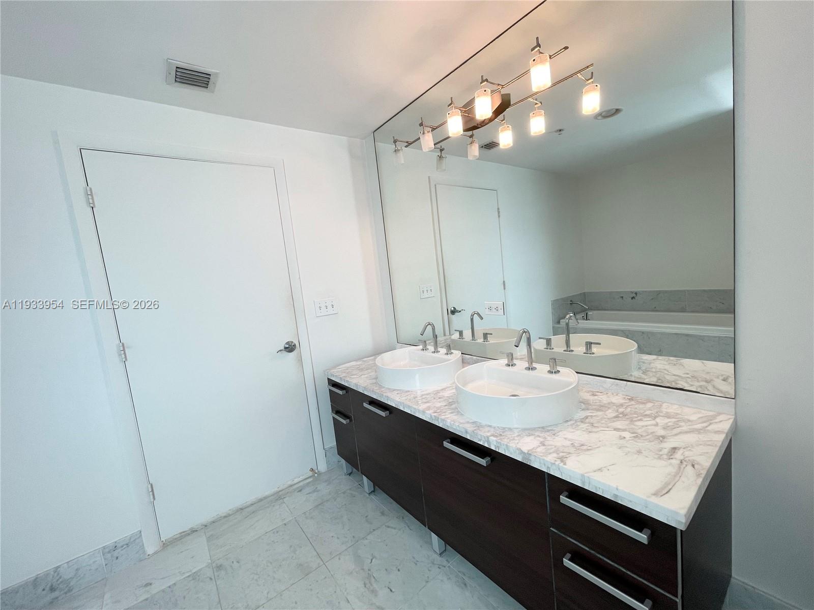 253 Northeast 2nd Street, Unit 2409 Miami, FL 33132 - Photo 37 of 61 a bathroom with a granite countertop sink a large mirror and vanity