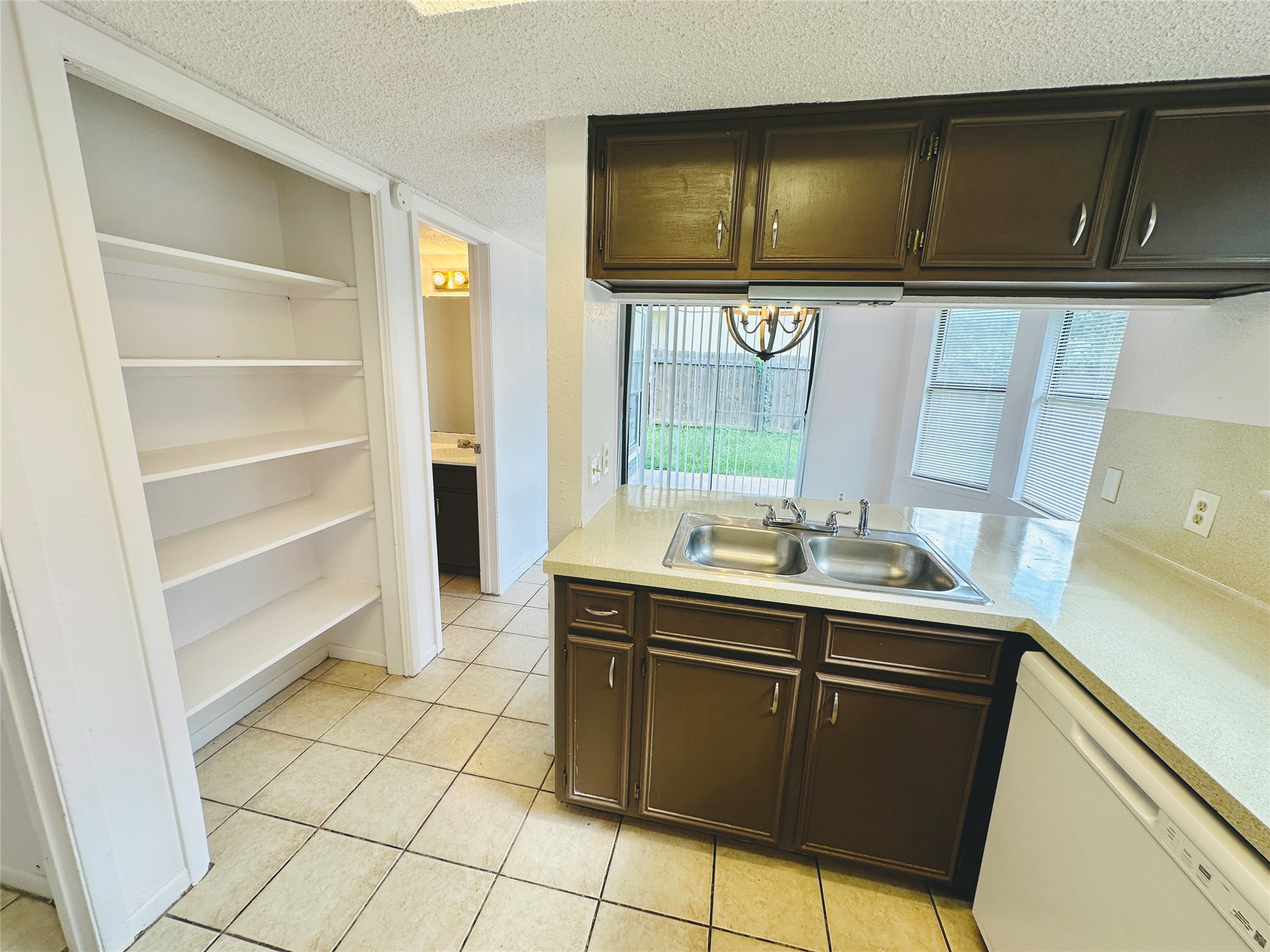 1002 Ridgemont Street Round Rock, TX 78664 - Photo 14 of 30 Kitchen featuring dishwasher, light countertops, a textured ceiling, light tile patterned flooring, and healthy amount of natural light
