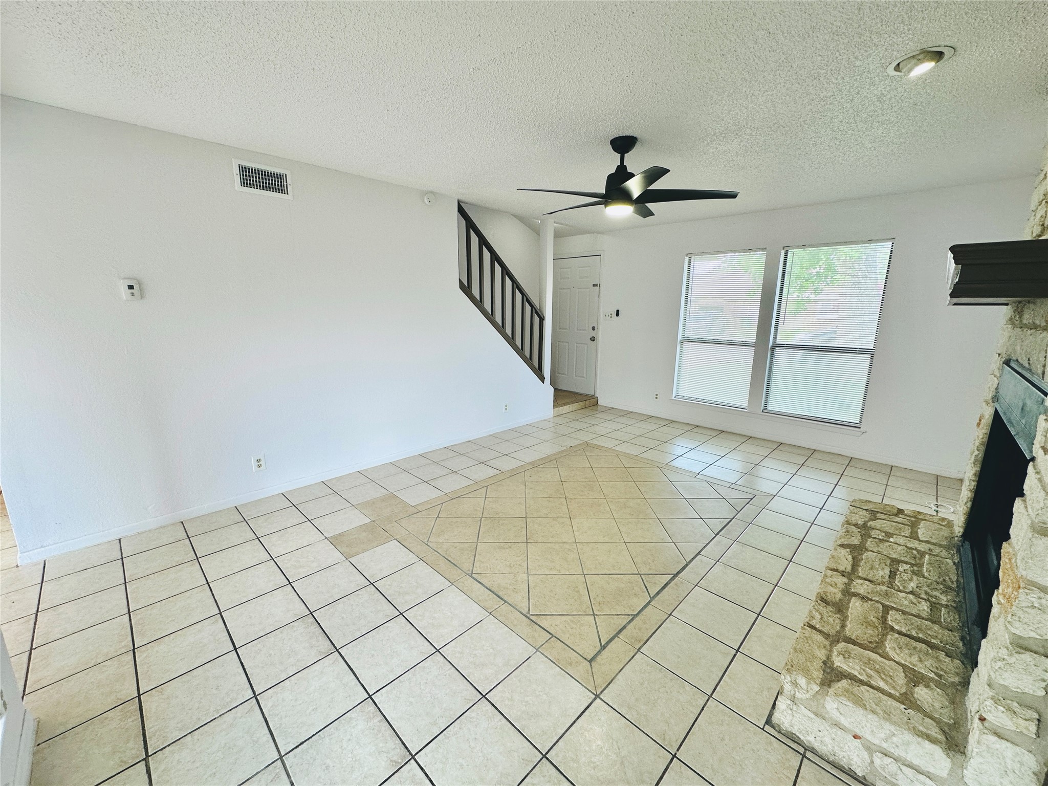 1002 Ridgemont Street Round Rock, TX 78664 - Photo 8 of 30 Unfurnished living room featuring light tile patterned floors, a textured ceiling, a fireplace, stairs, and ceiling fan