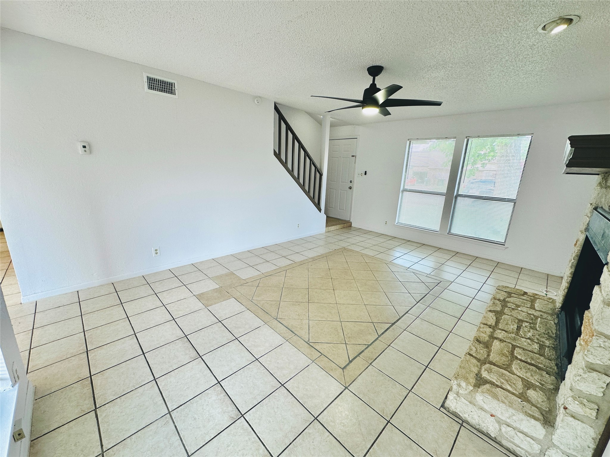 1002 Ridgemont Street Round Rock, TX 78664 - Photo 9 of 30 Unfurnished living room featuring a fireplace, light tile patterned flooring, a textured ceiling, stairs, and ceiling fan