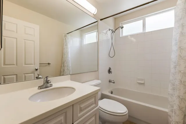 a bathroom with a granite countertop sink a toilet and shower