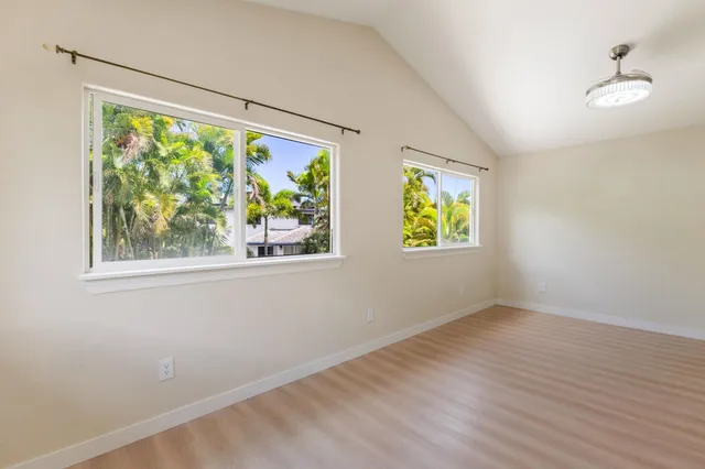 a view of an empty room with window and wooden floor
