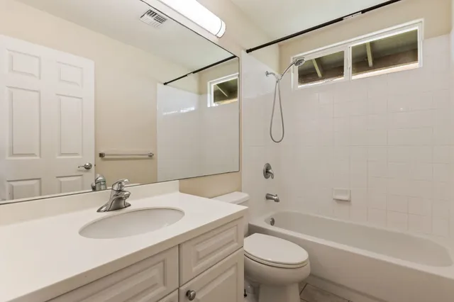 a bathroom with a granite countertop sink a toilet and shower