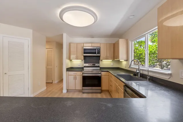 a kitchen with stainless steel appliances granite countertop a sink a stove and a refrigerator