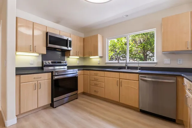 a kitchen with stainless steel appliances granite countertop a stove a sink and a microwave