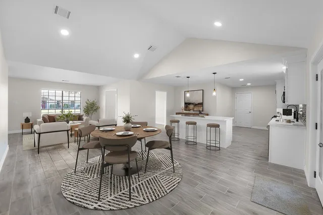 a living room with couches a dining table and kitchen view with wooden floor