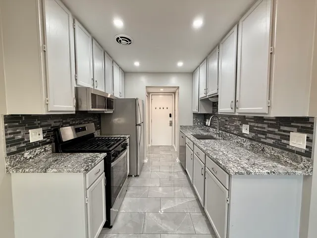 a kitchen with stainless steel appliances granite countertop a stove top oven a sink and dishwasher
