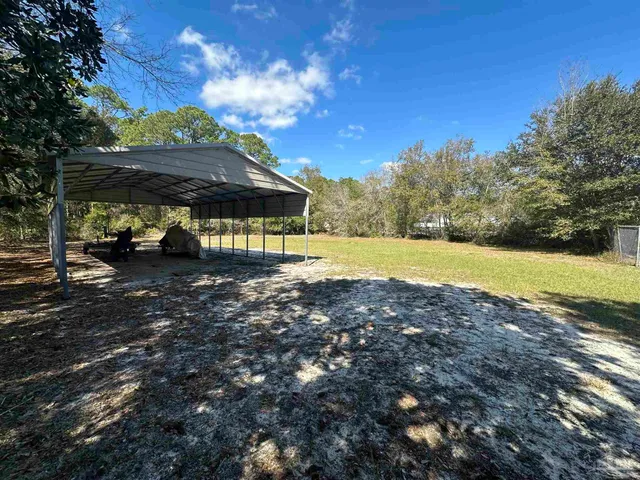 a view of a yard with table and chairs under an umbrella