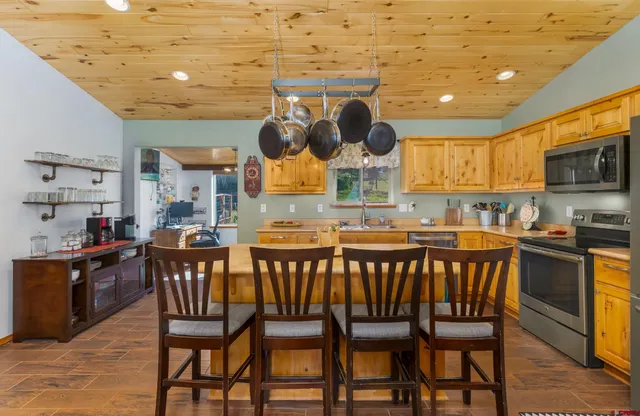 a kitchen with stainless steel appliances kitchen island granite countertop a table chairs in it and wooden floors