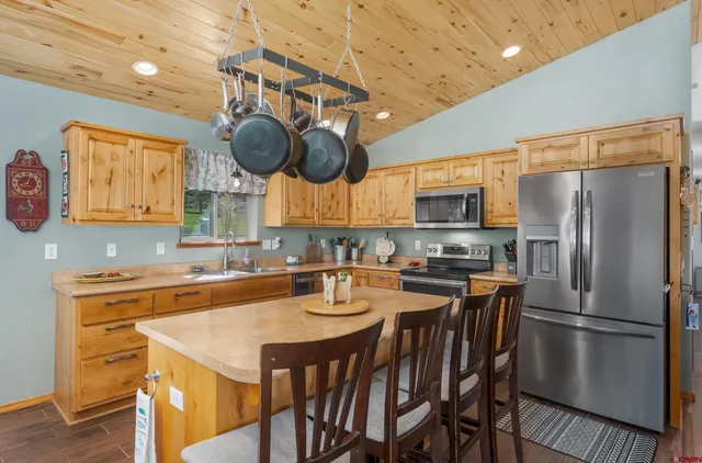 a kitchen with stainless steel appliances granite countertop a sink a stove a refrigerator cabinets and dining table