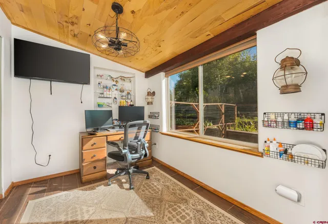 a work room with furniture a flat screen tv and a window