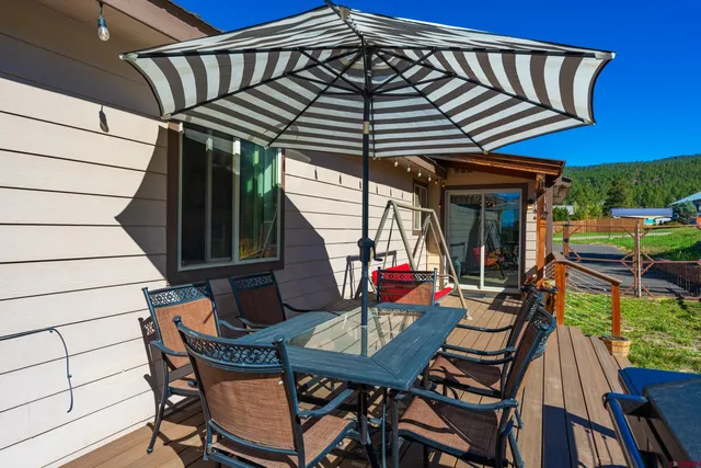 a roof deck with a dining table and chairs with wooden floor