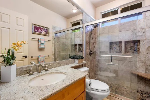 a bathroom with a granite countertop sink toilet a mirror and shower