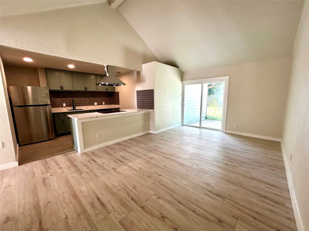 1005 West Martin Luther King Jr Boulevard Austin, TX 78701 - Photo 15 of 31 Kitchen featuring freestanding refrigerator, decorative backsplash, island exhaust hood, green cabinets, and high vaulted ceiling