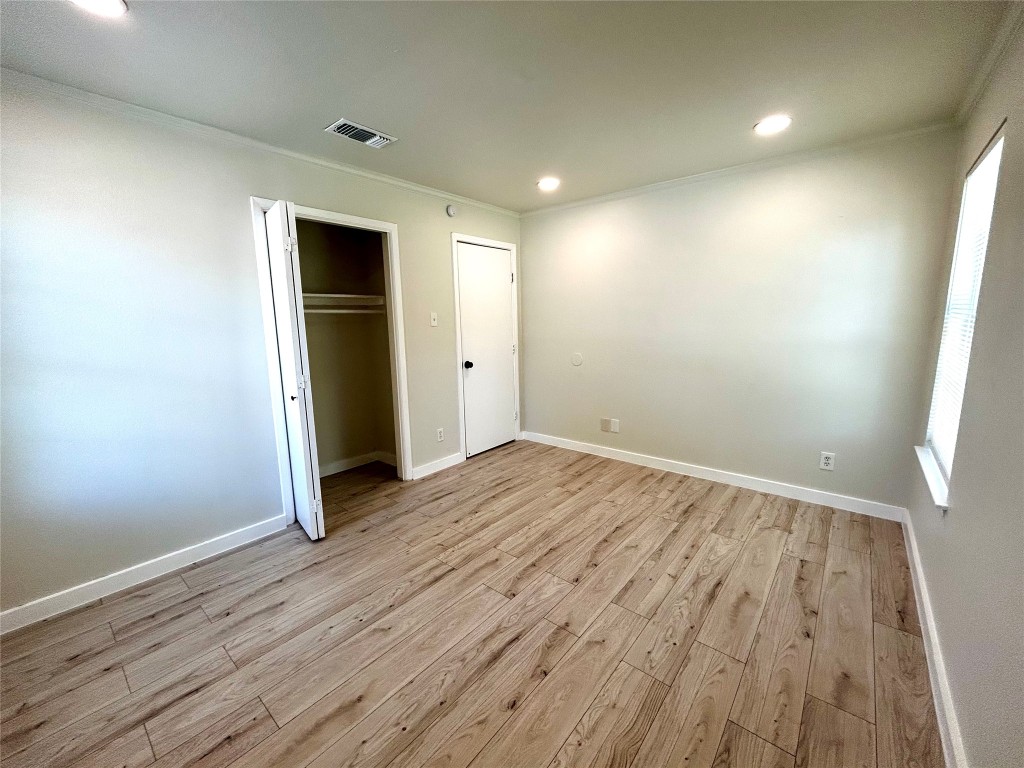 1005 West Martin Luther King Jr Boulevard Austin, TX 78701 - Photo 17 of 31 Unfurnished bedroom featuring crown molding, recessed lighting, light wood-style flooring, and a closet