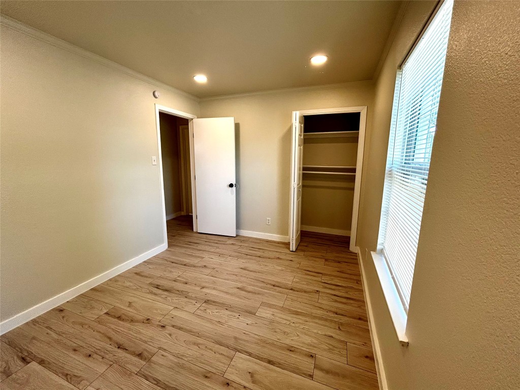 1005 West Martin Luther King Jr Boulevard Austin, TX 78701 - Photo 19 of 31 Unfurnished bedroom featuring light wood finished floors, ornamental molding, a closet, recessed lighting, and a textured wall