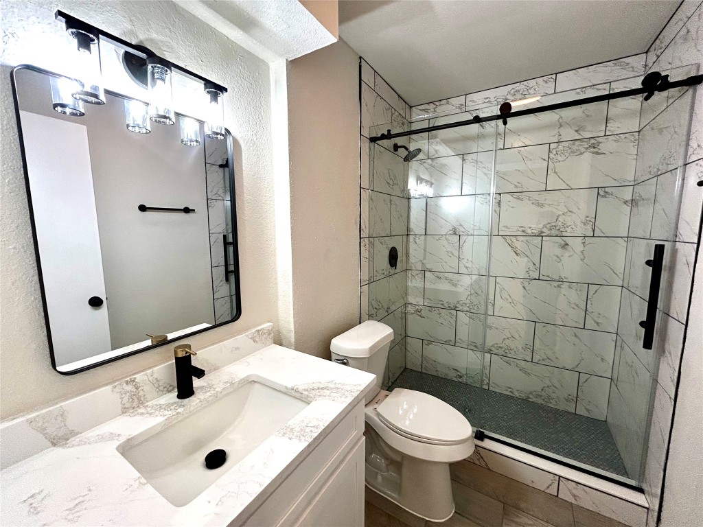 1005 West Martin Luther King Jr Boulevard Austin, TX 78701 - Photo 20 of 31 Bathroom with a textured wall, a stall shower, and vanity