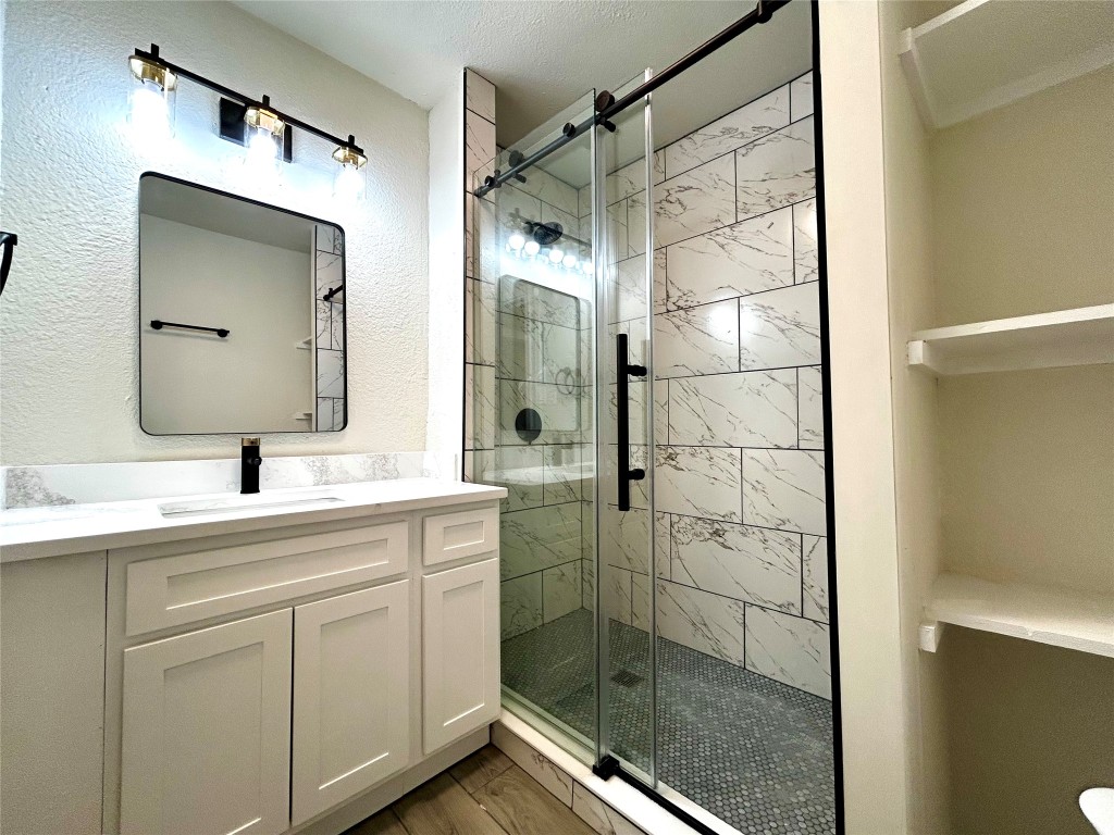 1005 West Martin Luther King Jr Boulevard Austin, TX 78701 - Photo 23 of 31 Full bath with a shower stall, vanity, a textured wall, and wood finished floors