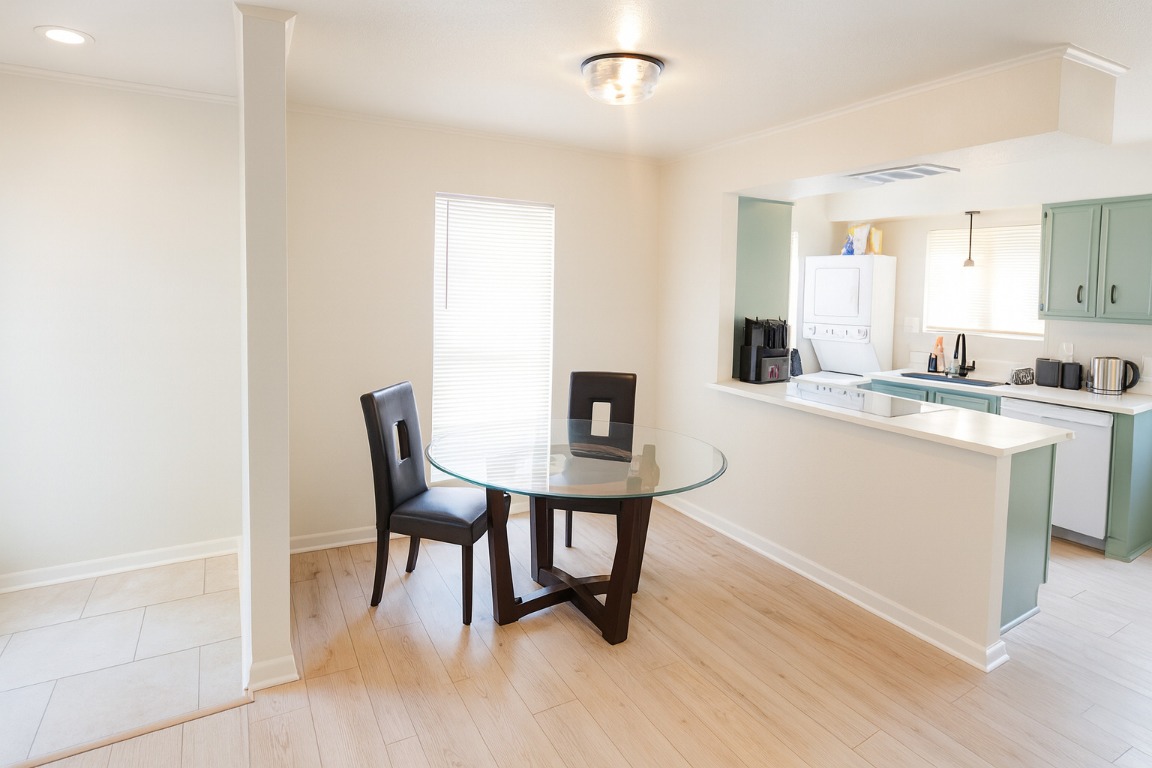 1005 West Martin Luther King Jr Boulevard Austin, TX 78701 - Photo 7 of 31 Dining space featuring stacked washer / drying machine, light wood finished floors, and ornamental molding