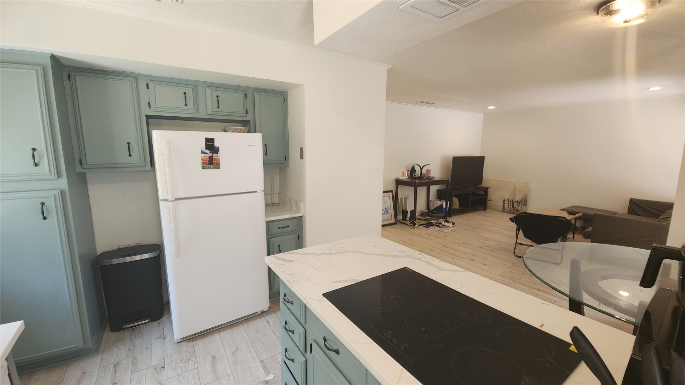 1005 West Martin Luther King Jr Boulevard Austin, TX 78701 - Photo 8 of 31 Kitchen with green cabinetry, light wood finished floors, freestanding refrigerator, light countertops, and recessed lighting