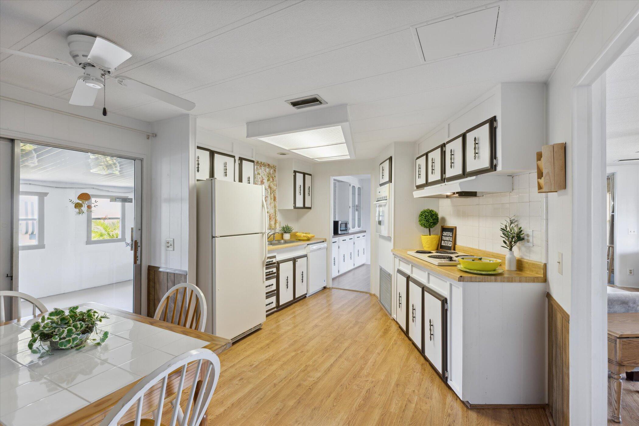 554 Ruth Circle Melbourne, FL 32904 - Photo 15 of 36 a kitchen with a refrigerator a stove a sink dishwasher and a dining table with wooden floor
