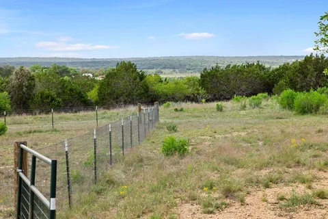 a view of a pathway both side of grassy field with trees