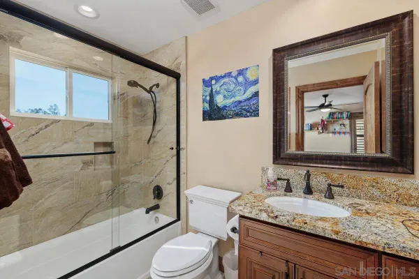 a bathroom with a granite countertop sink toilet and shower