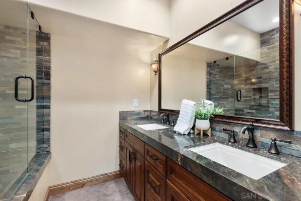 a bathroom with a granite countertop sink a mirror and shower