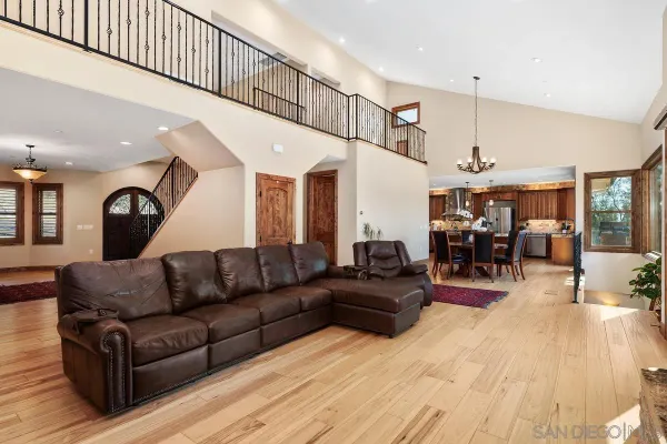 a living room with furniture kitchen view and a wooden floor