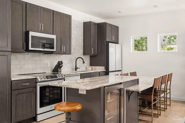 a kitchen with stainless steel appliances a stove a sink a microwave a dining table and chairs