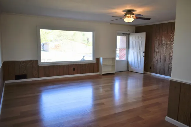 an empty room with wooden floor and windows