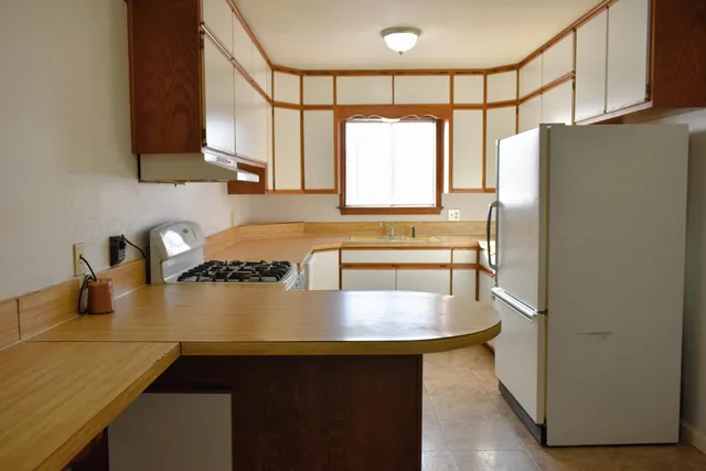 a kitchen with stainless steel appliances granite countertop a sink a refrigerator and a stove