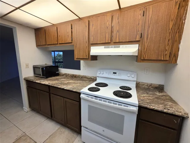 a kitchen with granite countertop wood cabinets and white appliances