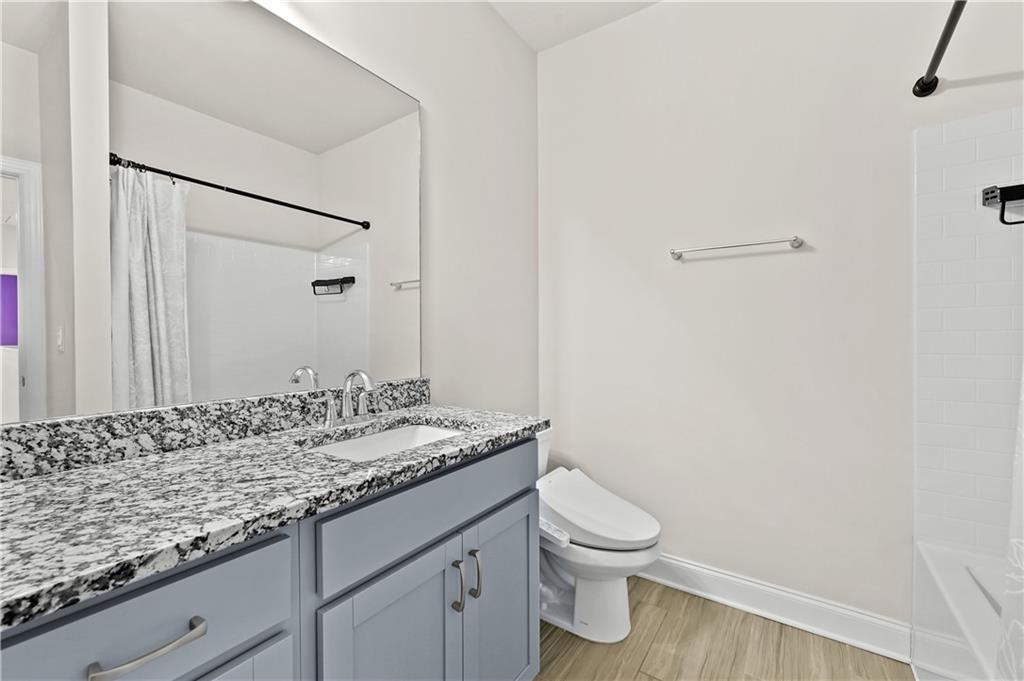 3475 Benedict Place Suwanee, GA 30024 - Photo 29 of 42 a bathroom with a granite countertop sink a toilet and a mirror