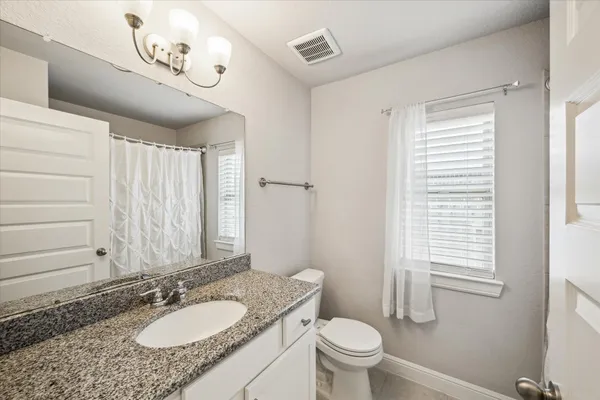 a bathroom with a granite countertop sink toilet and mirror