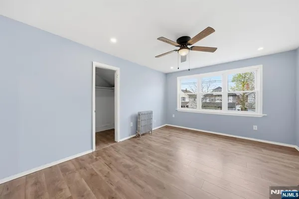a view of a room with a ceiling fan and hardwood floor