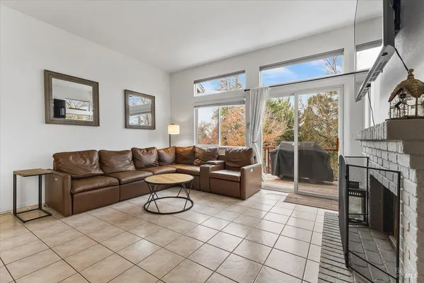 a living room with furniture a fireplace and a floor to ceiling window
