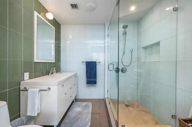 a bathroom with a double vanity sink a toilet and shower