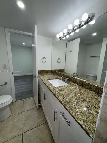 a bathroom with a granite countertop sink a toilet and a mirror