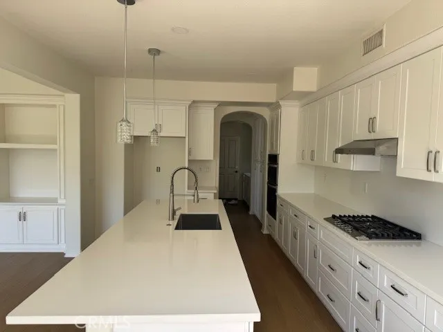 a kitchen with stainless steel appliances kitchen island a white counter space a sink and cabinets