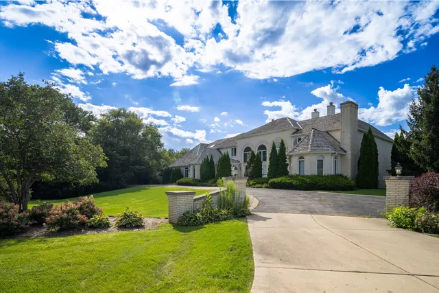 a view of a house with a big yard plants and large tree